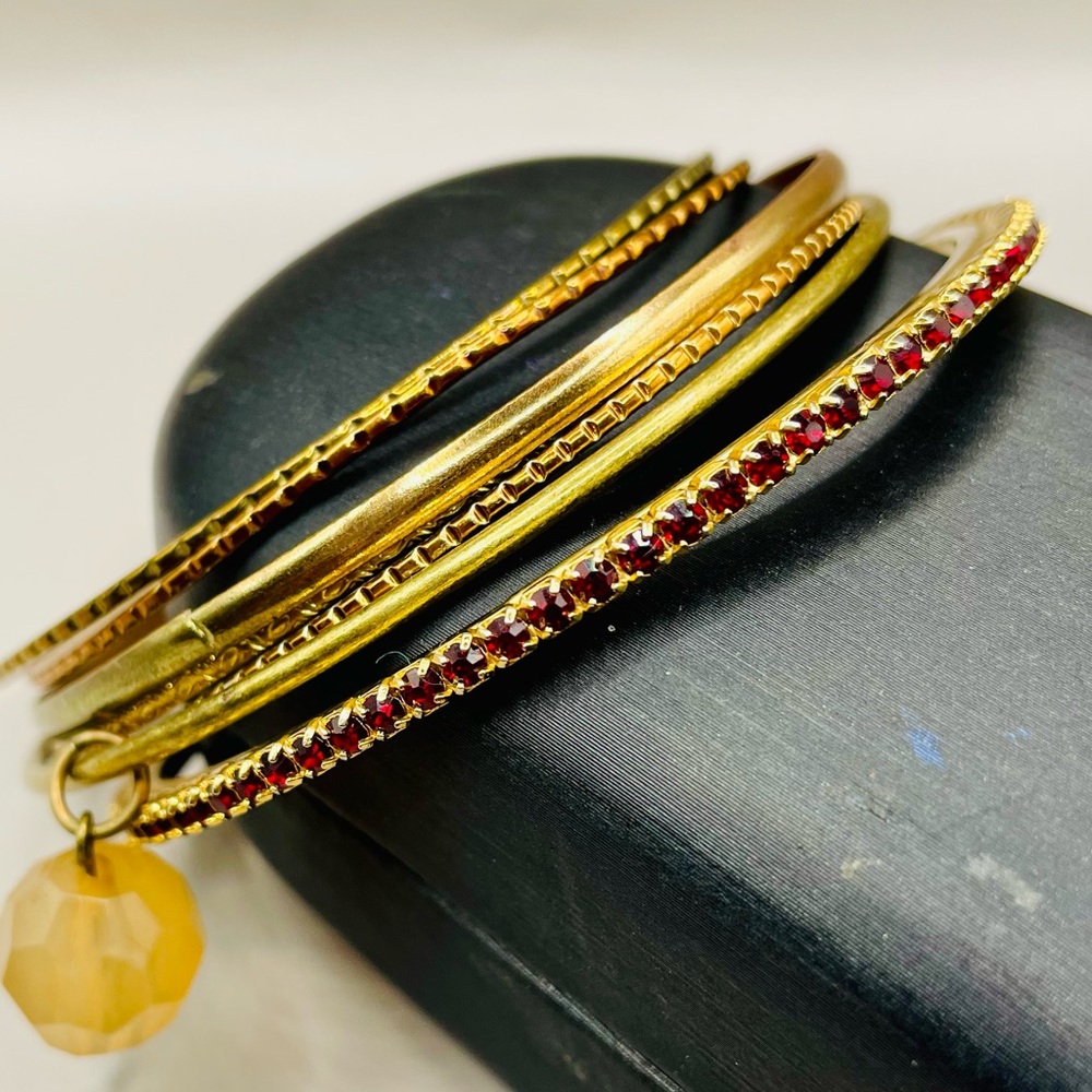 Stack of 7 bangles. One has red rhinestones and one has a bead charm. Boho